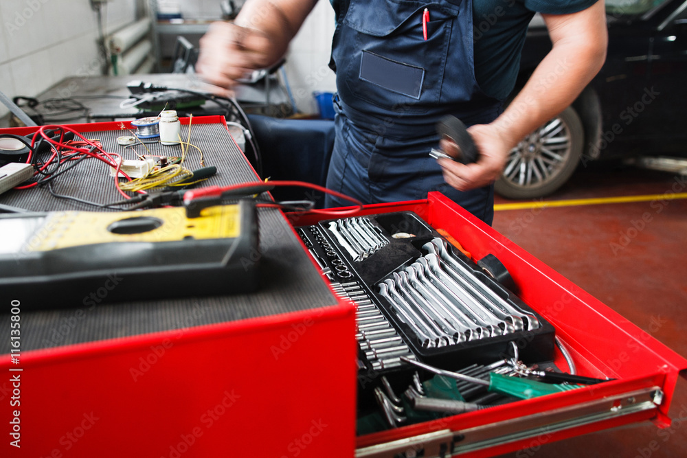 Wall mural Professional toolbox with modern tools at garage. Mechanic taking facilities from special box for mechanical instruments