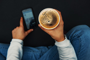 Girl with a smartphoen taking a black coffee