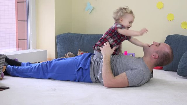 Lovely baby girl sits on dad stomach and embrace loving father.