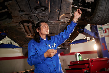 Repairman with tablet computer doing car diagnostic