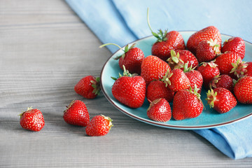 Ceramic plate with strawberries at old wooden table in daylight. Close up, high resolution product. Harvest Concept