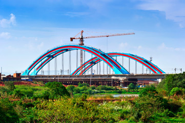 Construction of a new bridge with a high construction crane on a background sky