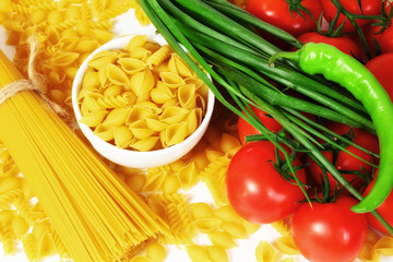 Different types of raw Italian pasta with tomatoes and other vegetables. Top view background.
