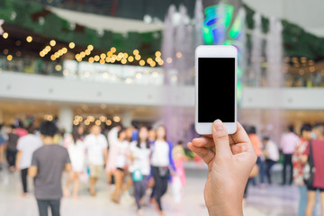 Obraz premium Smart phone with white screen in hand on blurred in shopping mall background,shopping online concept,shopping by smart phone