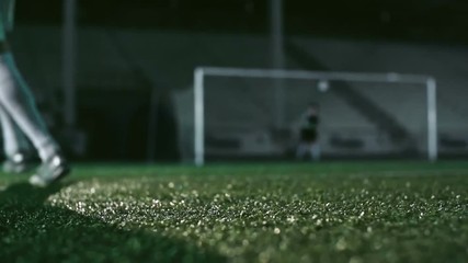 Low angle view of feet of soccer player kicking wet ball on misty grass in the night stadium in slow motion - Powered by Adobe
