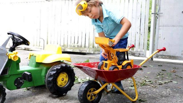 4 j&auml;hriger Junge spielt mit Sand, Wasser, Traktor, Bagger und Scheibtruhe