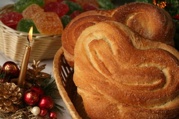 close-up of sweet rolls in the shape of hearts in a wicker basket and Christmas decorations on a white tablecloth in the studio