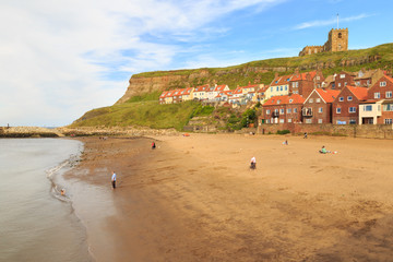 WHITBY, ENGLAND - JULY 16: Various people on the beach, young boy playing in the edge of the sea. In Whitby, North Yorkshire, England. On 16th July 2016.