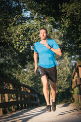 Fitness man running at city park. Male strongl athlete exercising outdoor.