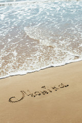 The inscription on the sand seashore. The name on the sand. Against the backdrop the sea waves.