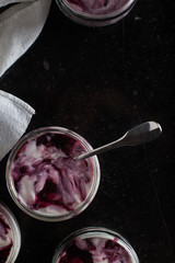 Yogurts with fruits assortment in glass bowls on dark marble background. Natural and fruit healthy, diet, gourmet dessert for granola breakfast. Sweet yoghurts closeup.