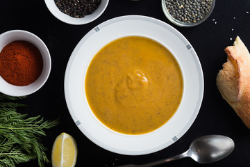 Cream soup of assorted lentil. Yellow and green lens, spices as raw for meal and lemon on black background. Healthy, appetizing, delicious, vegetarian food. Top view, copy space.
