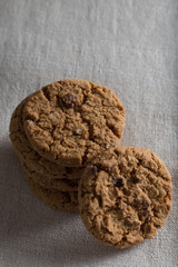 Cookies pile with chocolate chip on light textile background. Delicious morning snacks for breakfast, brunch and lunch. Appetizing, healthy, sweet, scrummy, and fast food.