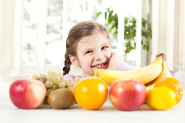 Happy child standing with fruit on table