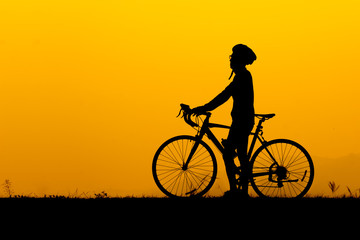 Fototapeta na wymiar A silhouette of man standing with bicycle