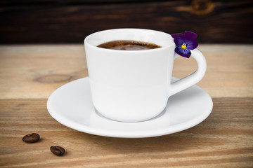 Cup of espresso with coffee beans on wooden table