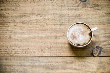 Cup of cafe latte or cappuccino on wooden table. Top view