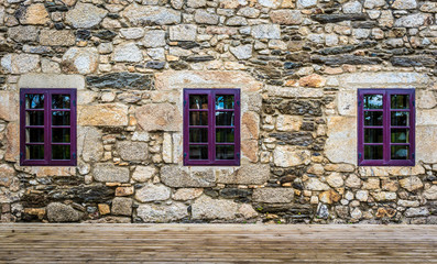 Purple window on medieval castle made of stone and rocks.