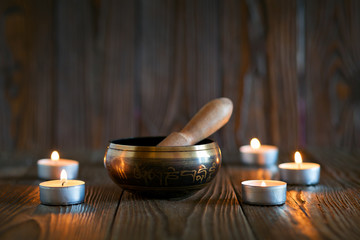 singing bowl on dark wooden background. Burning candles and oil for aromatherapy and massage..