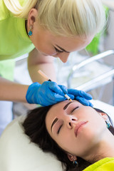 professional cosmetologist preparing young woman for permanent e