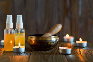 singing bowl on dark wooden background. Burning candles and oil for aromatherapy and massage..