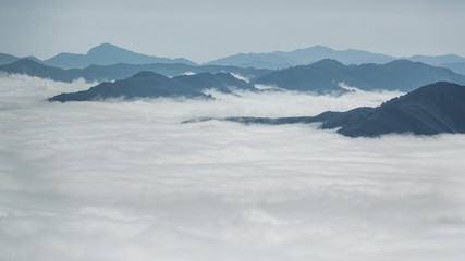 Fototapeta na wymiar Over the clouds and fog among mountain summits landscape
