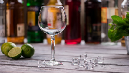 Empty glass and ice cubes. Lime on wooden surface. Ingredients for cool beverage. How about a cocktail.