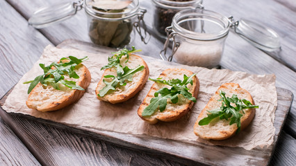 Pieces of grilled baguette. Bread and arugula leaves. Preparation of simple snack. Fresh and crispy appetizer.