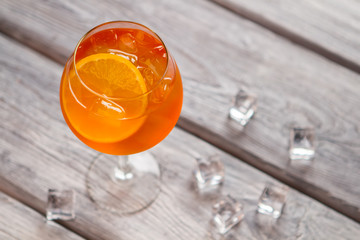 Orange cocktail in wineglass. Ice cubes on wooden background. Proven recipe of aperol spritz....