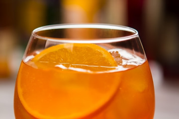 Glass with orange beverage. Slice of fresh orange. Aperol spritz served at nightclub. Alcohol and soda water.