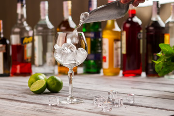 Scoop with ice over wineglass. Limes near ice cubes. Preparing a cool drink. You need to freshen up.
