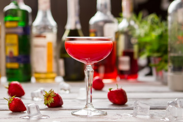 Red beverage in a glass. Ice cubes and strawberries. Refreshment after hard day. Clover club cocktail with juice.