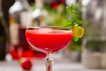 Glass with red beverage. Mint sprig and lemon peel. Proven recipe of clover club. Dense cocktail with egg white.