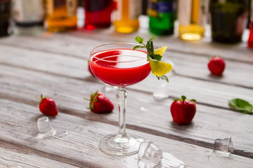 Bright red cocktail in glass. Ice cubes are melting. Clover club with imported gin. Delicious alcoholic cocktail and berries.
