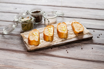 Liquid pours on baguette slice. Jar with whole pepper. How to prepare italian snack. Grilled bread and olive oil.
