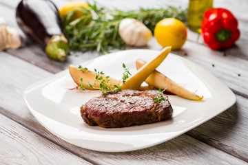 Cooked meat with salt. Herb and slices of pear. Ribeye steak served at restaurant. Delicious dish rich in protein.