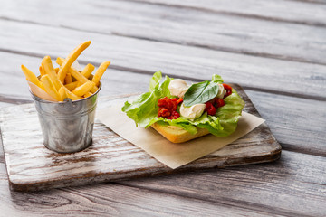 Small bucket filled with fries. Red sauce and basil leaf. New recipe of sandwich. Add some basil for aroma.