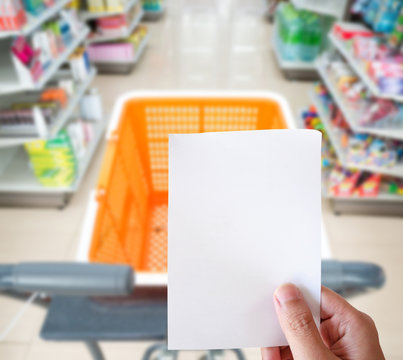 hand holding shopping list paper with shopping cart at supermark