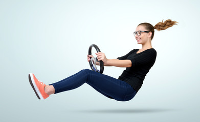 Young girl in glasses driver car with a wheel on background