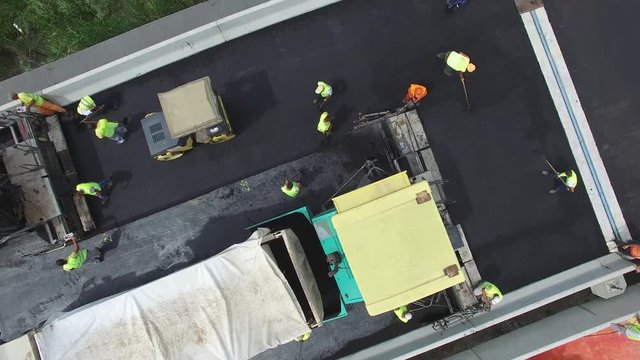 Aerial view on workers with heavy machines working on bridge reconstruction.
