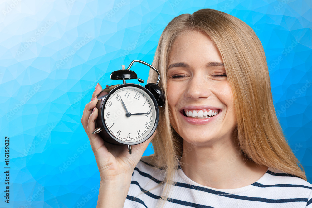 Wall mural Young smiling woman holds black clock