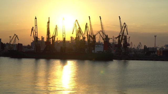 Sunset at the seaport. Wieden ship under unloading, the sun reflected in the Sea