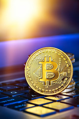 Photo Golden Bitcoins (new virtual money )close-up on a blue background with a computer keyboard.