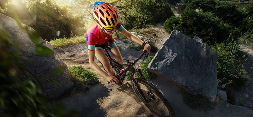 Obraz premium Sport. Cyclist riding a bike on an off road to the sunset. Top view