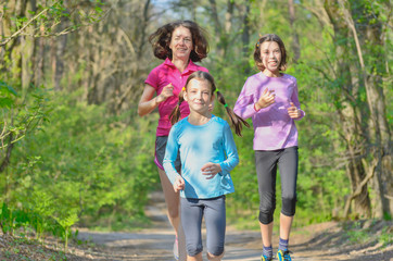Family sport, happy active mother and kids jogging outdoors, running in forest
