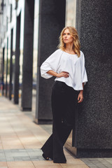 Young pensive business lady in white blouse and black pants