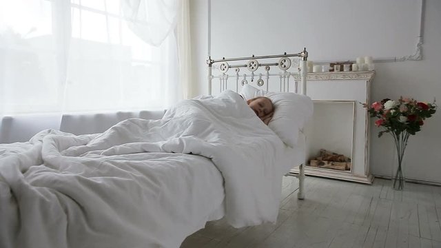 Young girl sleep in bed sheltered white blanket.The child sleeps in a beautiful white bedroom.Child in a beautiful white room sleeping on the bed