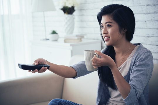 Mixed-race Woman Drinking Coffee And Watching Tv At Home