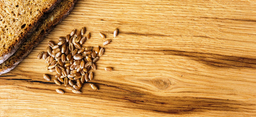 Obraz na płótnie Canvas slices of bread with wheat grains on wooden board from above