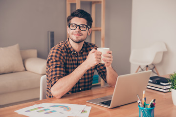 Young handsome man in glasses drinking coffee in office and drea